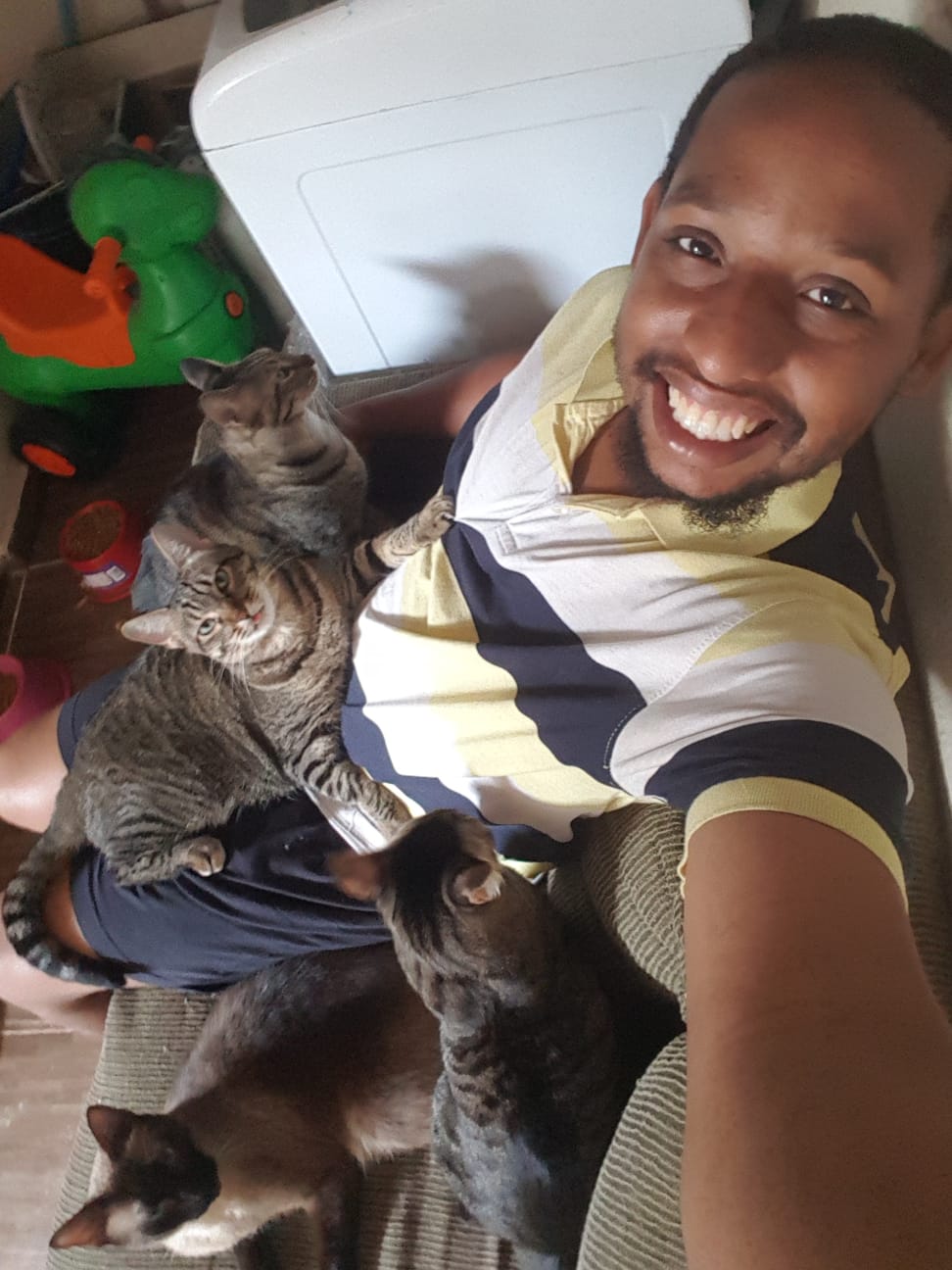 Julio com vários gatos ao seu redor em casa